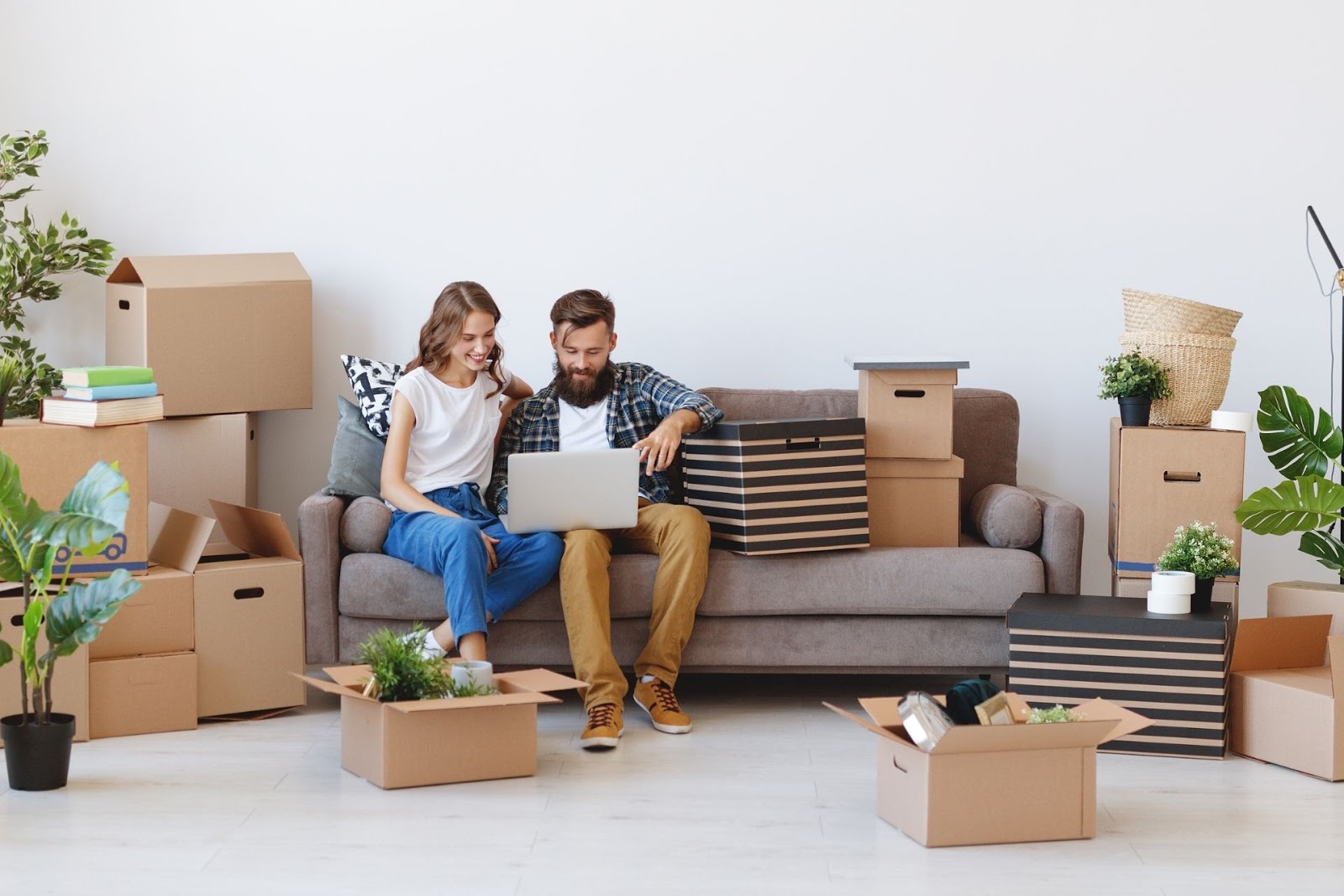 Two people sitting on a couch surrounded by boxes 