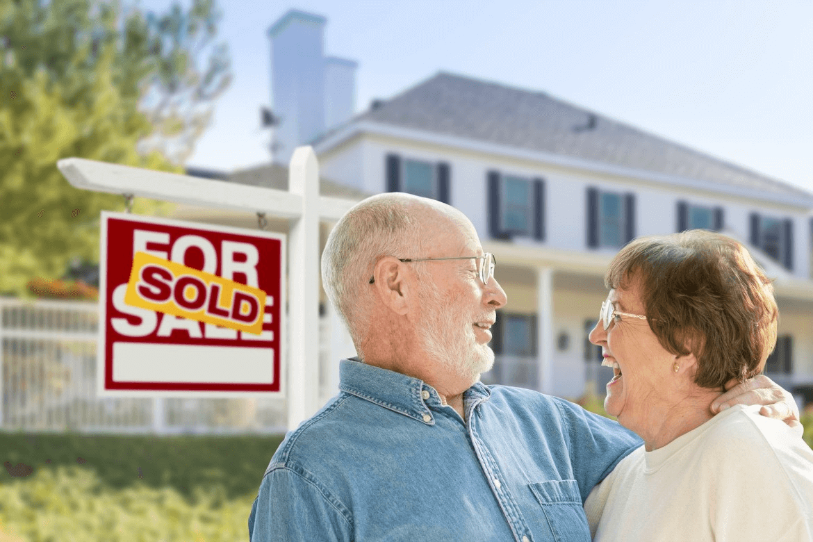 Happy elderly couple stands in front of their sold family home